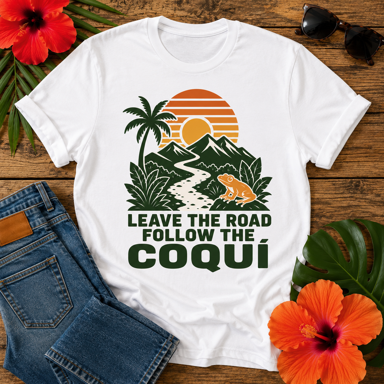 Coquí Sunset T-Shirt featuring a tropical sunset, mountains, palm tree, coquí frog, and the quote "Leave the Road Follow the Coquí"